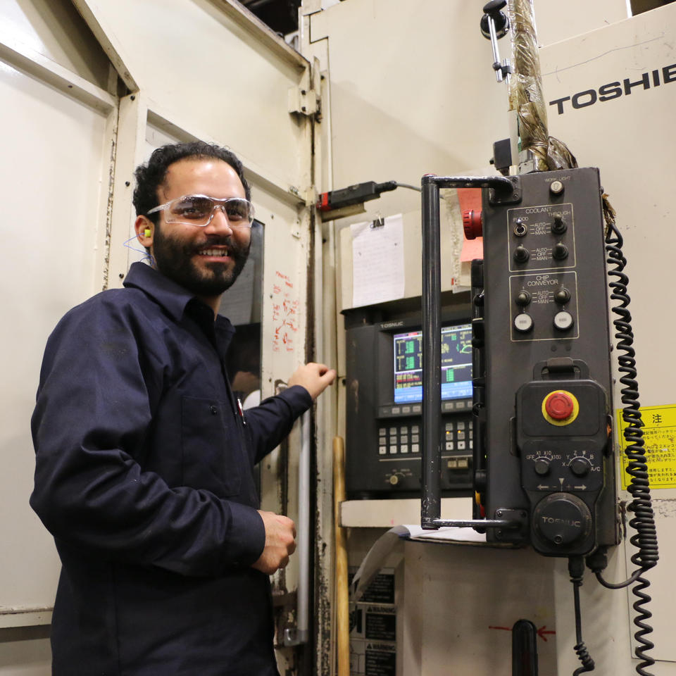 CNC Machinist standing at the control panel on a Toshiba Mill machine running a gear case part at the Sovereign Road Location.