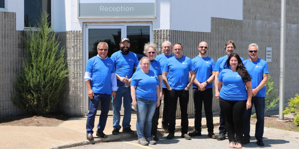The office staff standing in front of the head office Piper Lane location of ADJ Industries in London, Ontario.