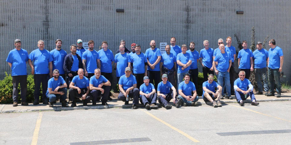 Employees standing infront of the 2068 Piper Lane location of ADJ Industries in London, Ontario.