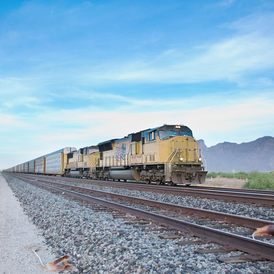 Freight train. Railroad rail tracks. Mountain landscape in the bacground. Locomotive / railway stock image licensed to ADJ Industries Inc.